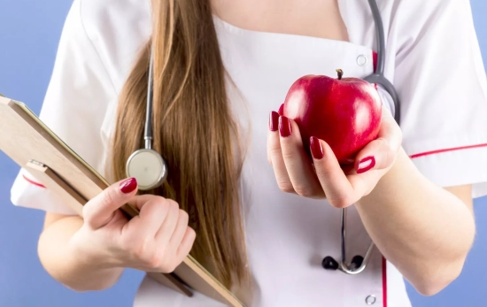 Una experta sostiene una manzana, que puede ayudar a reducir el colesterol / FREEPIK