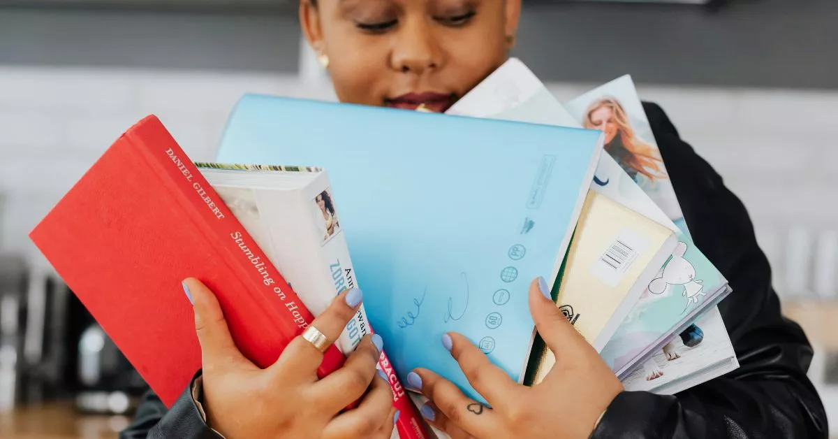 Una persona con un libro de autoayuda y otras obras / PEXELS