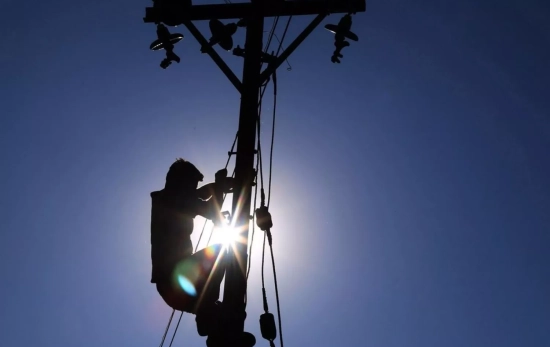 Una persona subida a un poste eléctrico de luz / Sanjay Baid - EFE Una persona subida a un poste eléctrico de luz / Sanjay Baid - EFE