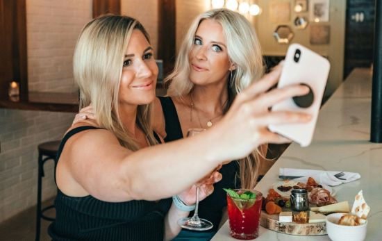 Dos mujeres adjuntando un selfie a ChatGPT para realizar un trend viral / UNSPLASH