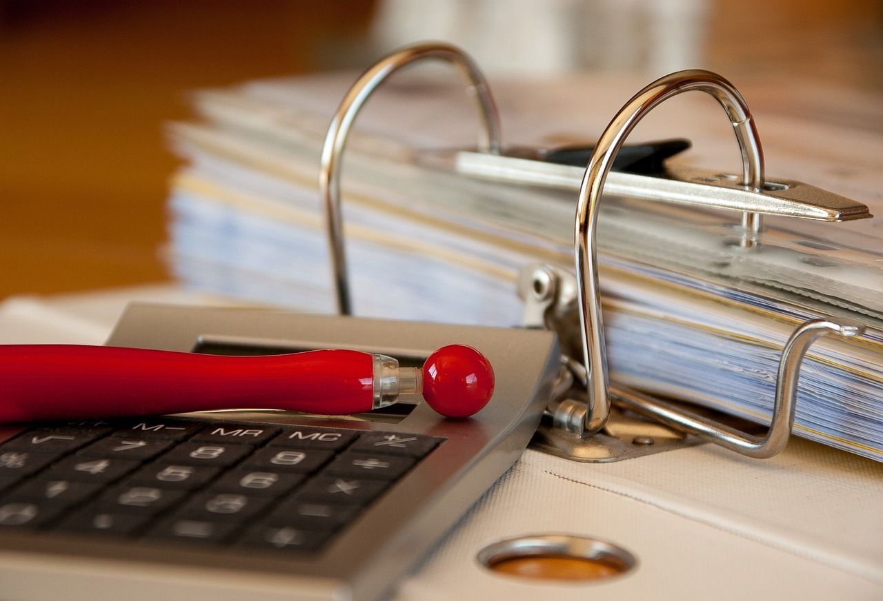 Calculadora, bolígrafo y archivador con documentos