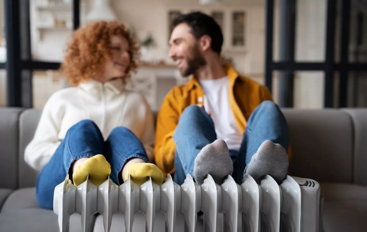 Dos personas con un radiador eléctrico / FREEPIK