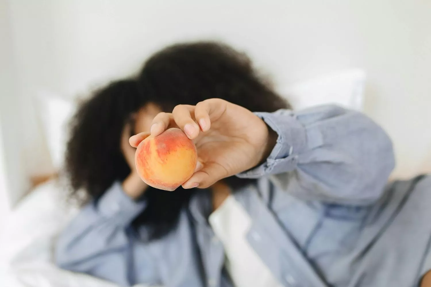 Una chica disfruta de una fruta mientras descansa/ PEXELS