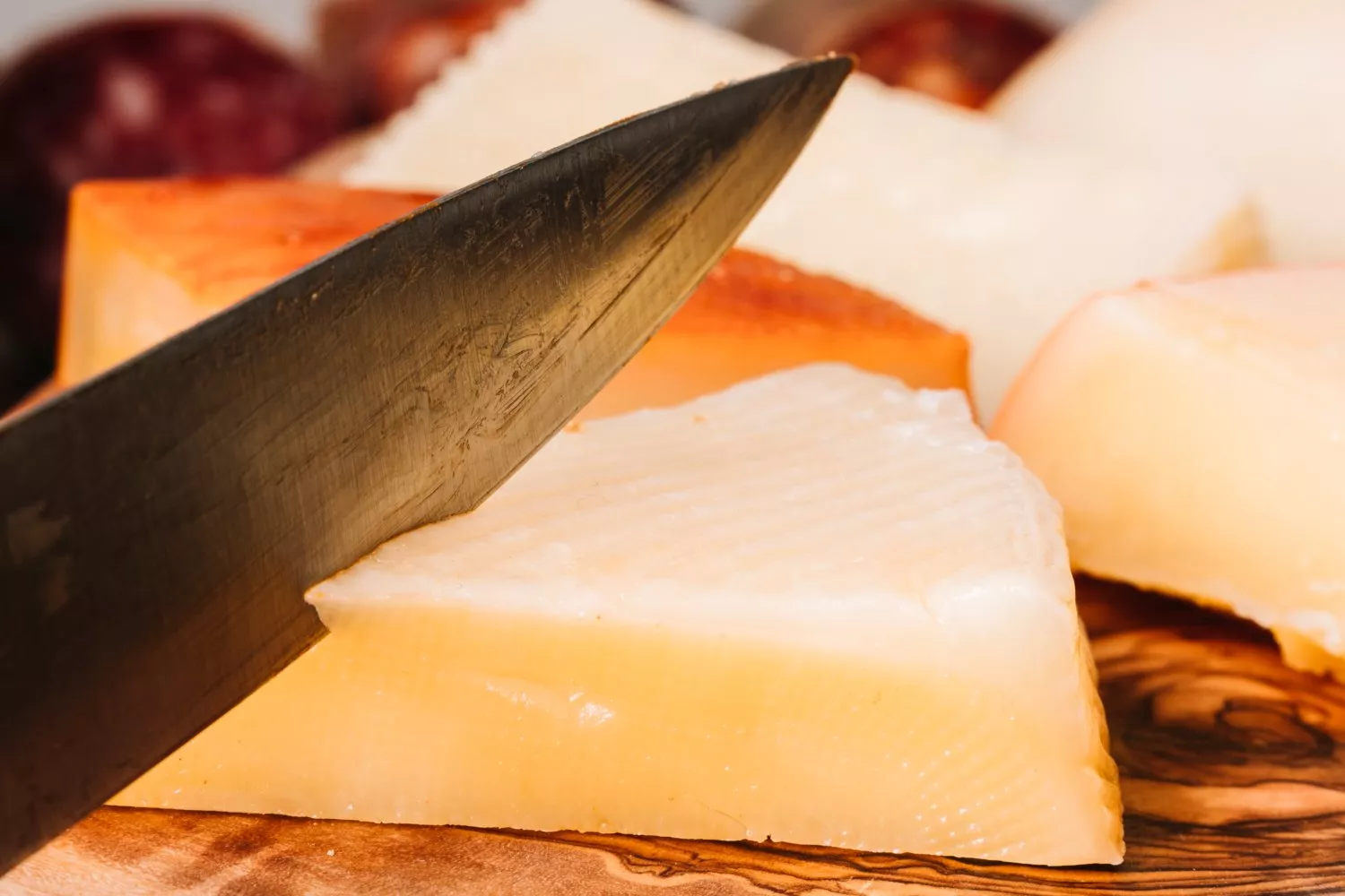Una persona parte un queso / FREEPIK