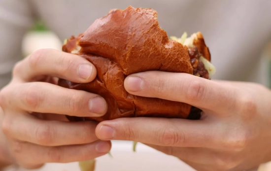 Un consumidor sostiene una hamburguesa, la enemiga de tu energía / PEXELS Un consumidor sostiene una hamburguesa, la enemiga de tu energía / PEXELS