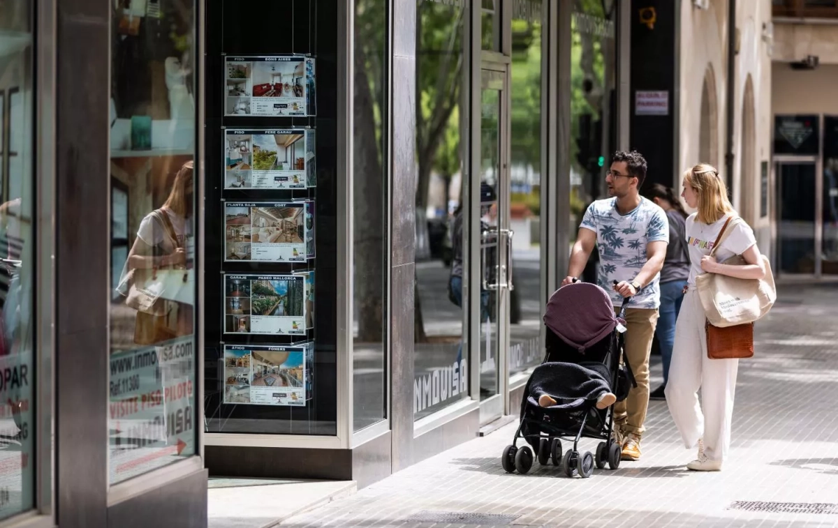 Dos personas observan los anuncios de viviendas en venta en una inmobiliaria Dos personas observan los anuncios de viviendas en venta en una inmobiliaria