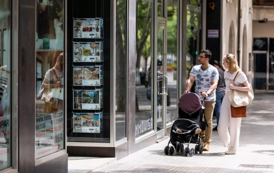 Dos personas observan los anuncios de viviendas en venta en una inmobiliaria Dos personas observan los anuncios de viviendas en venta en una inmobiliaria