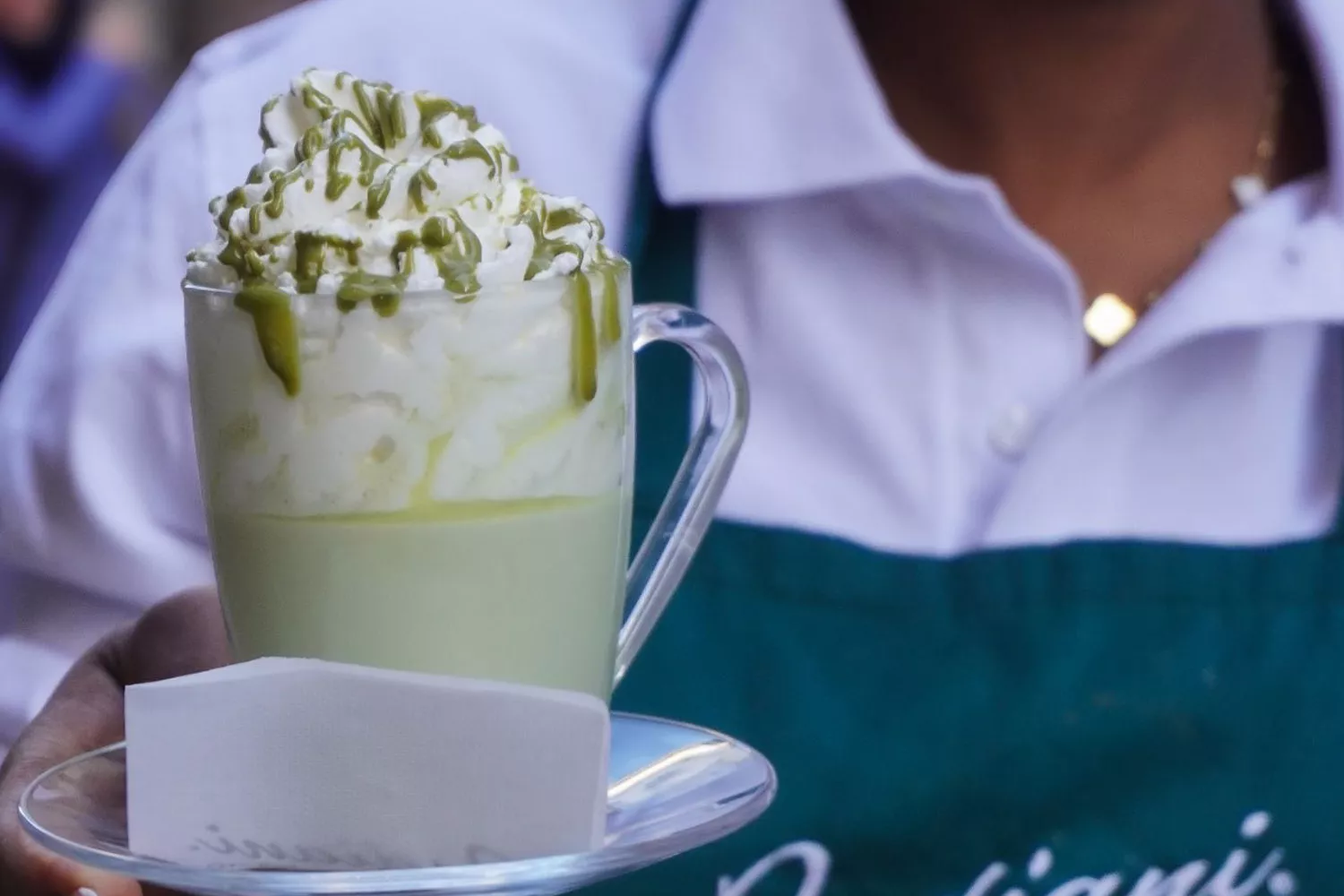 Una empleada con una taza de pistacho caliente / BADIANI