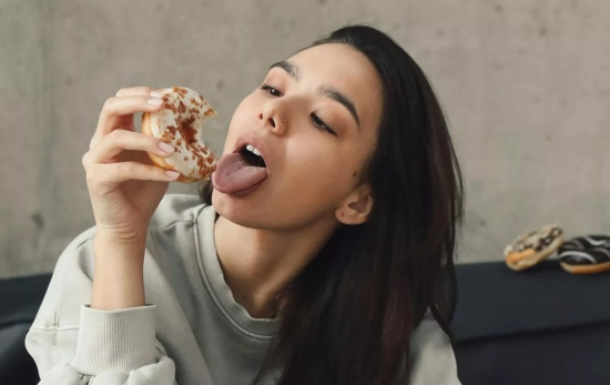 Una chica comiéndose un donut en el sofá/ PEXELS Una chica comiéndose un donut en el sofá/ PEXELS