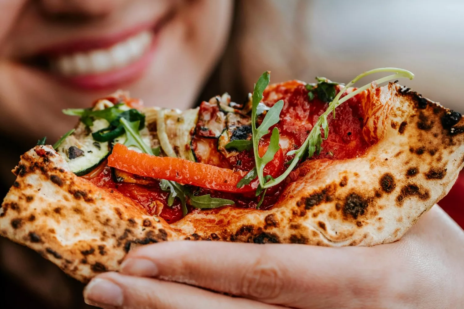 Una chica con un trozo de pizza / PEXELS