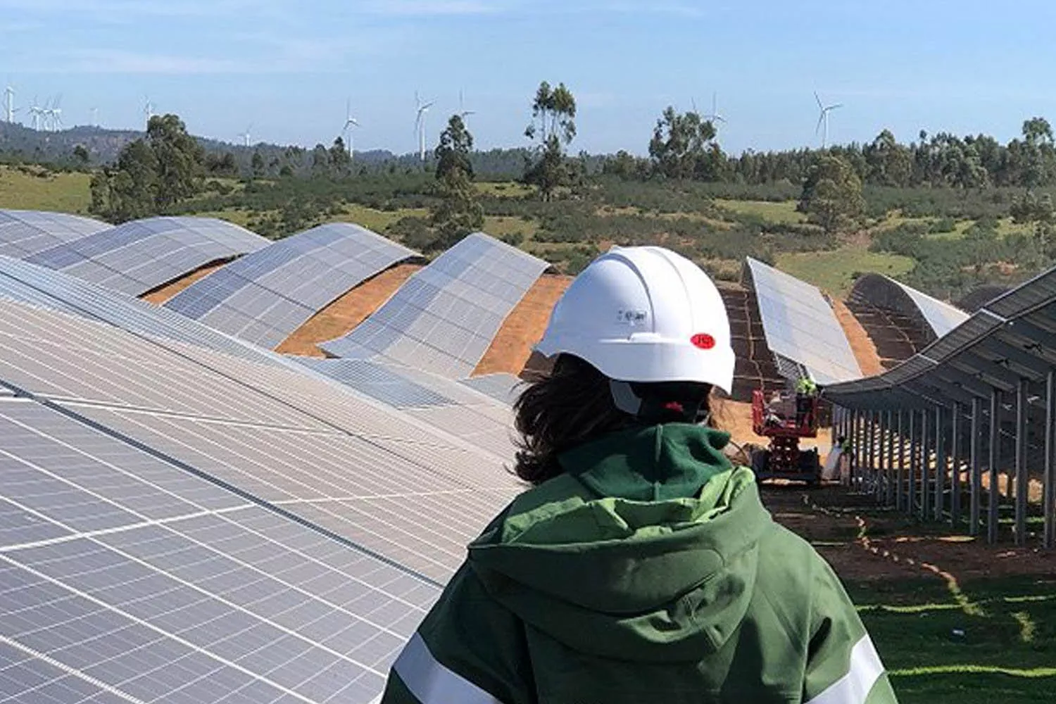 Una trabajadora de una de las empresas más éticas del mundo junto a paneles solares y molinos al fondo / IBERDROLA