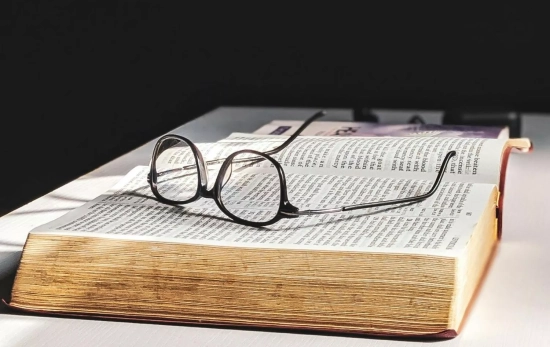 Un libro con unas gafas de lectura encima/ PEXELS
