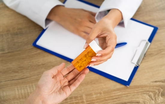 Un profesional tiende a un paciente un bote con medicamentos / FREEPIK Un profesional tiende a un paciente un bote con medicamentos / FREEPIK