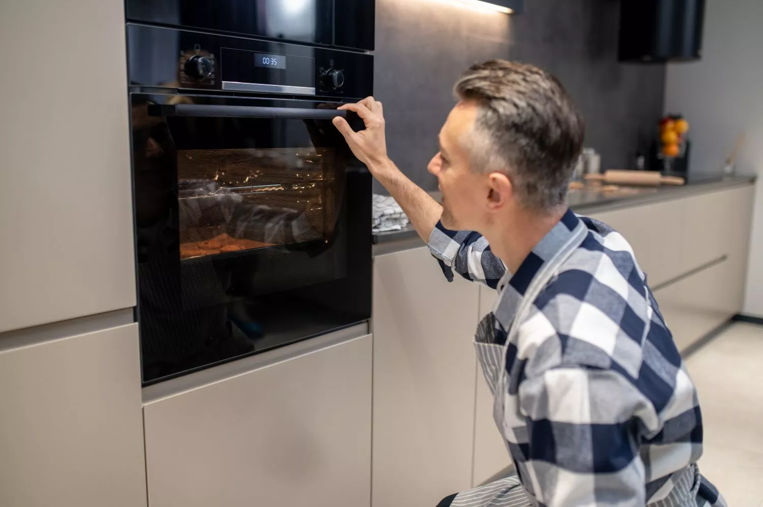 Un hombre observa los alimentos en el interior de su horno
