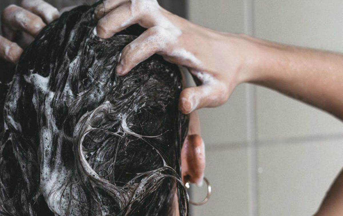 Una mujer se lava el pelo con champú / PEXELS