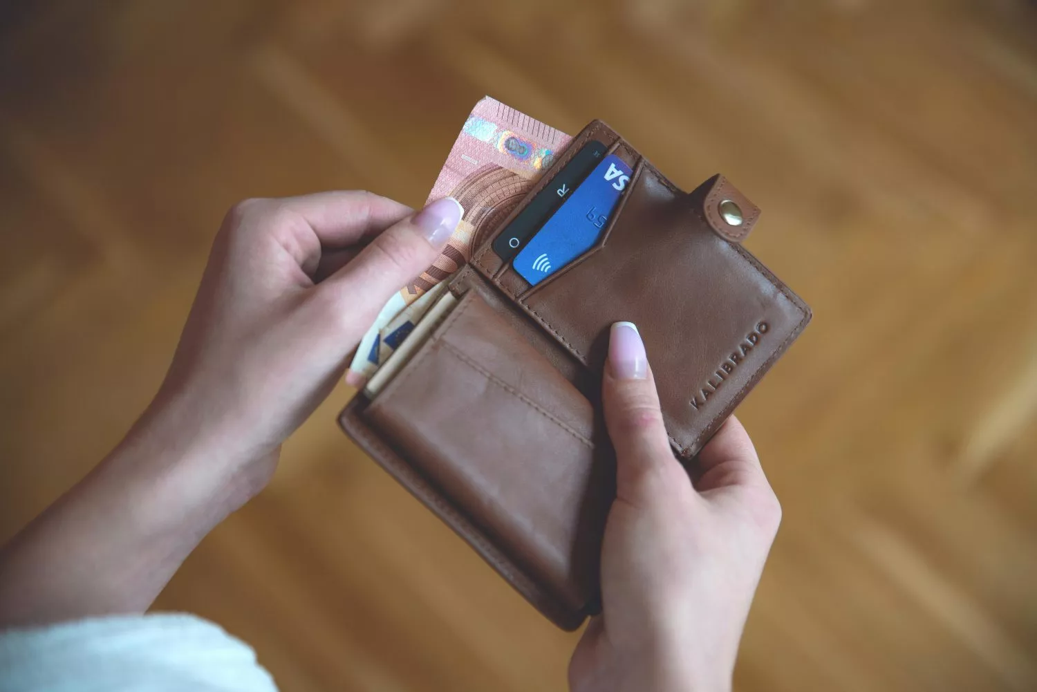 Una persona saca dinero en efectivo de su tarjeta   PEXELS