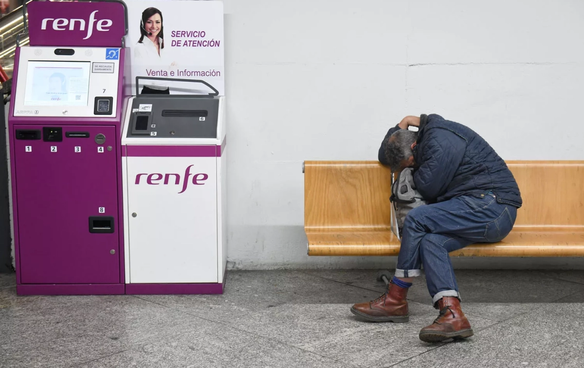Un hombre en una silla de la estación de Atocha Almudena Grandes, tras los retrasos en los trenes AVE, junto a una máquina de Renfe / FERNANDO SÁNCHEZ - EP Un hombre en una silla de la estación de Atocha Almudena Grandes, tras los retrasos en los trenes AVE, junto a una máquina de Renfe / FERNANDO SÁNCHEZ - EP