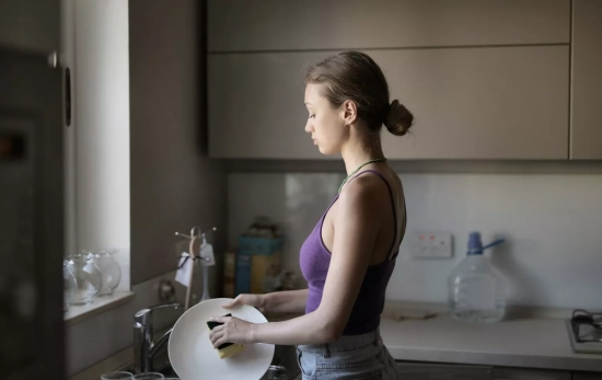 Una mujer friega los platos / FREEPIK - @wirestock