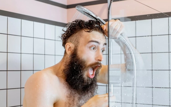 Una persona duchándose con agua fría, que se ha quedado sin agua caliente en casa por una avería/ CANVA Una persona duchándose con agua fría, que se ha quedado sin agua caliente en casa por una avería/ CANVA