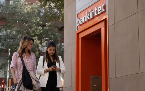 Dos personas pasan frente a un banco / EP - DAVID ZORRAKINO Dos personas pasan frente a un banco / EP - DAVID ZORRAKINO