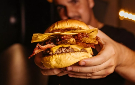 Una persona sostiene una hamburguesa / UNSPLASH Una persona sostiene una hamburguesa / UNSPLASH