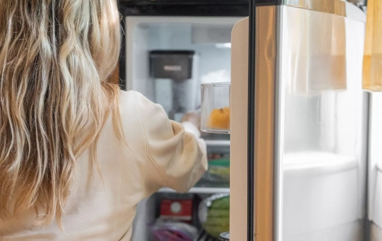 Una chica que ya sigue los consejos de Consumidor Global para cómo colocar sus alimentos en la nevera/ CANVA Una chica que ya sigue los consejos de Consumidor Global para cómo colocar sus alimentos en la nevera/ CANVA