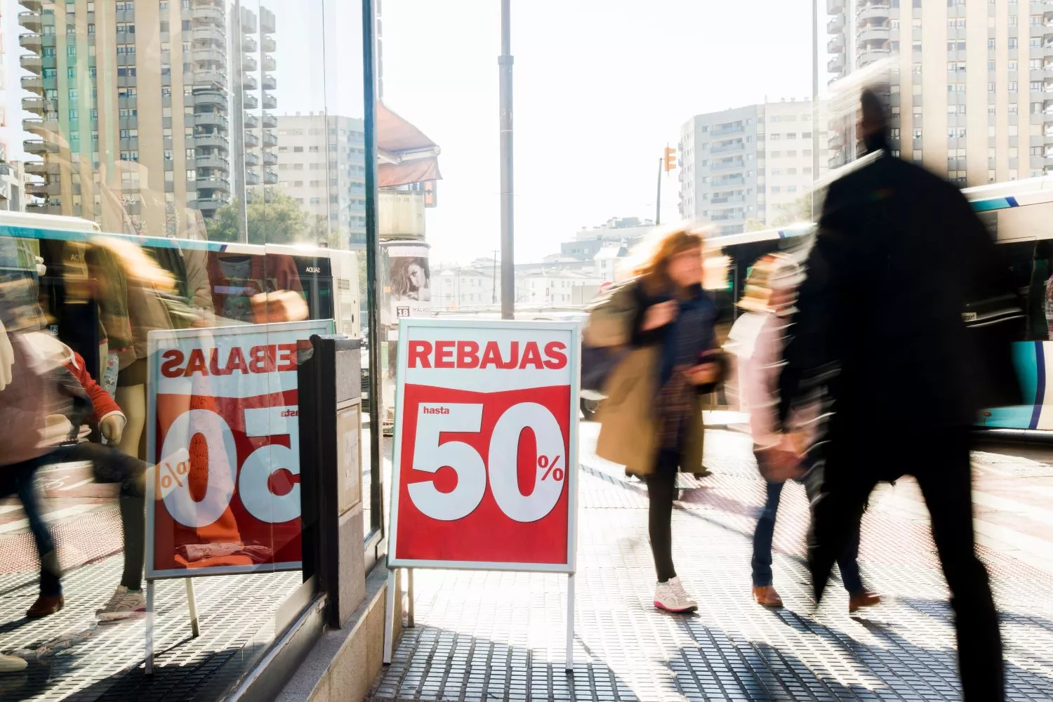 Consumidores españoles junto a un cartel que anuncia rebajas
