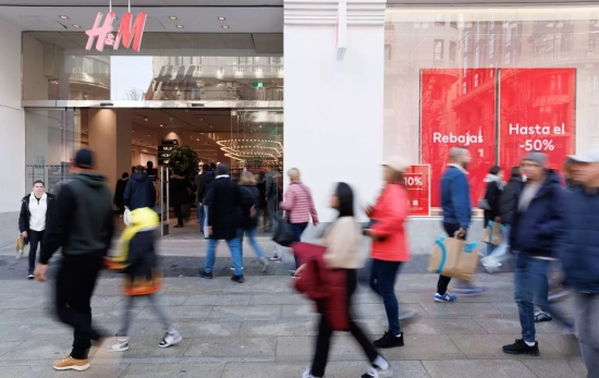 Varias personas caminan frente a una tienda de H&M, Varias personas caminan frente a una tienda de H&M,