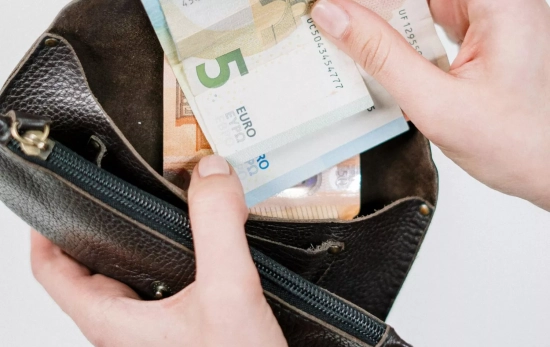 Una persona guarda billetes en un monedero Una persona guarda billetes en un monedero