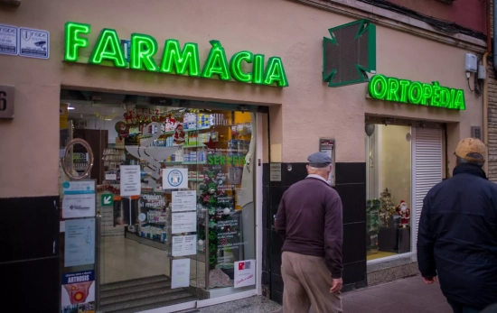 Varias personas pasan al lado de una farmacia Varias personas pasan al lado de una farmacia
