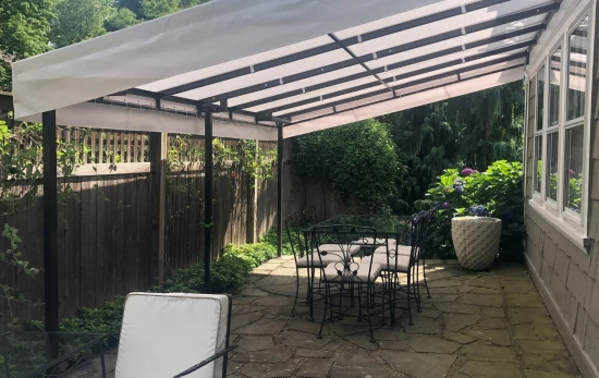 Una casa protegida con toldo y vegetación para refrescar la orientación del sol en la fachada/ CANVA Una casa protegida con toldo y vegetación para refrescar la orientación del sol en la fachada/ CANVA