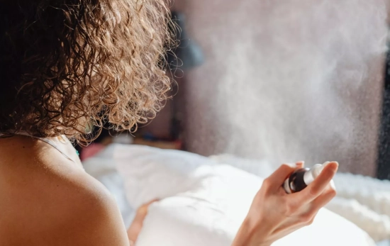 Una chica rociando las sábanas con una solución casera de suavizante / CANVA Una chica rociando las sábanas con una solución casera de suavizante / CANVA