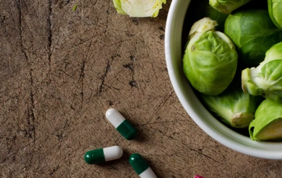 Unas pastillas junto a un plato con alimentos vegetales Unas pastillas junto a un plato con alimentos vegetales