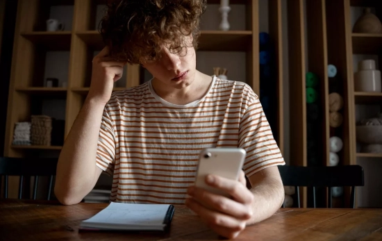 Un joven mira su teléfono Un joven mira su teléfono