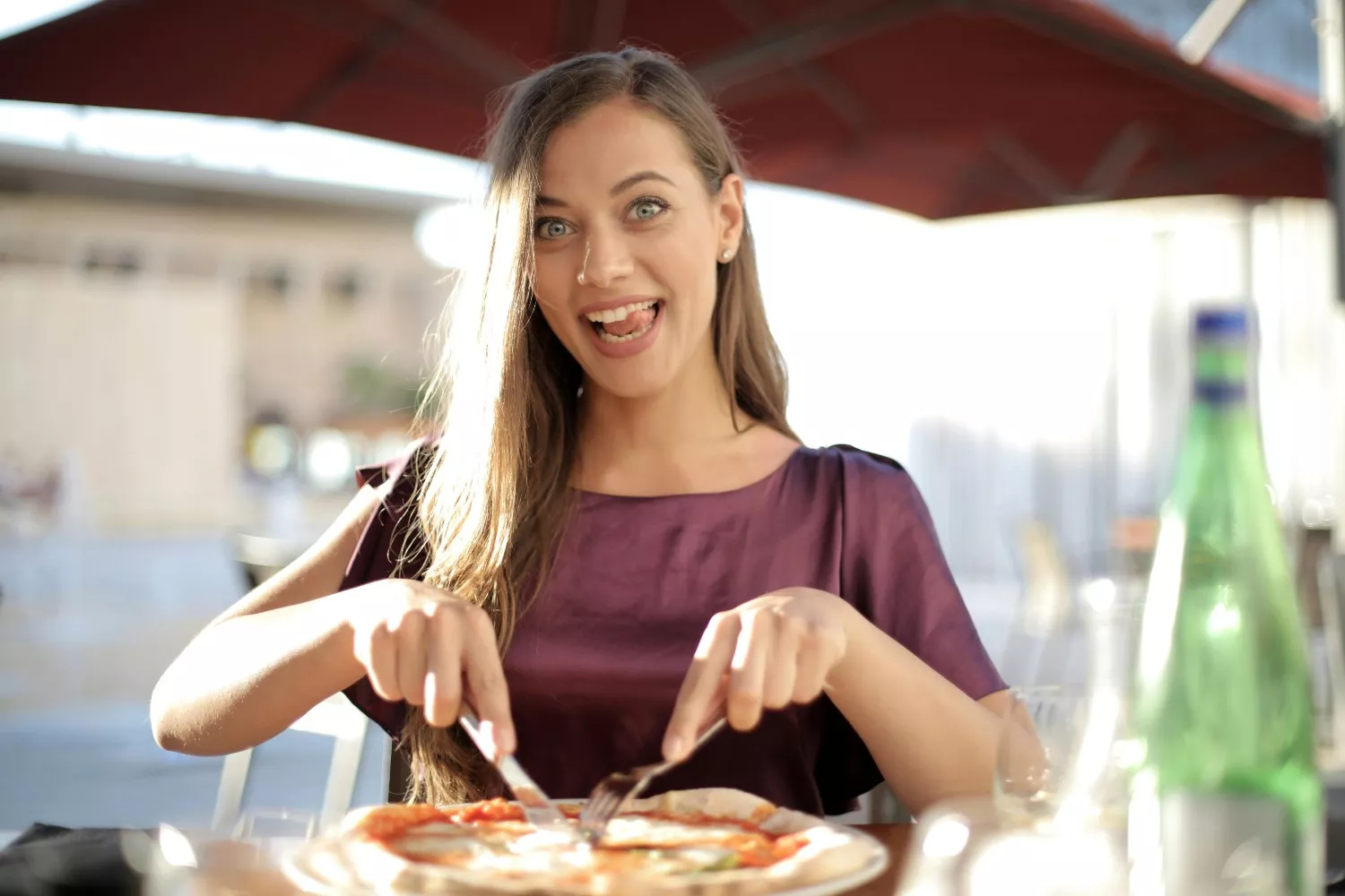 Una persona parte una pizza con cubiertos / PEXELS