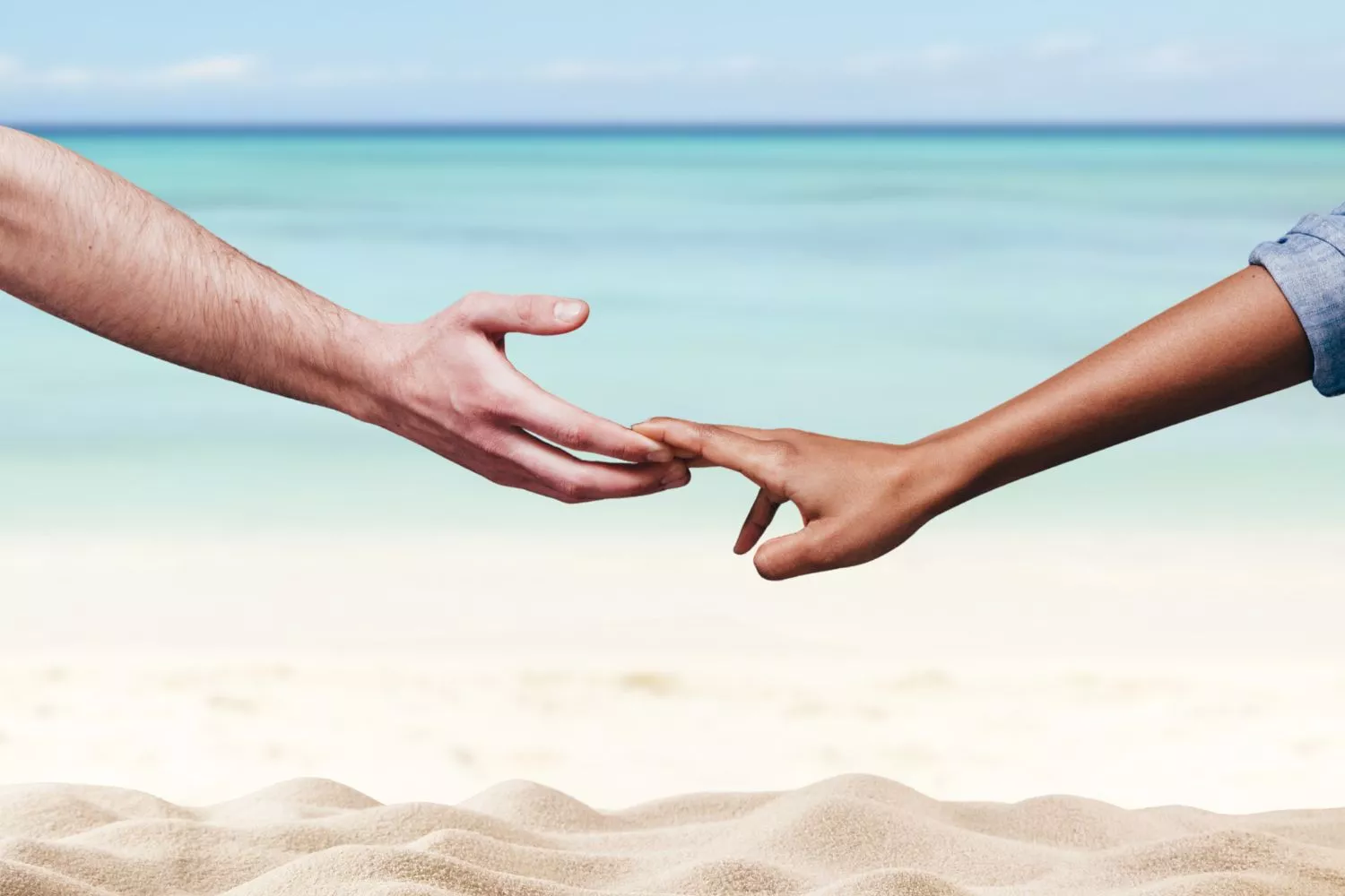 Dos personas se dan la mano en la playa tras hacer un curso de psicología / Montaje Consumidor Global