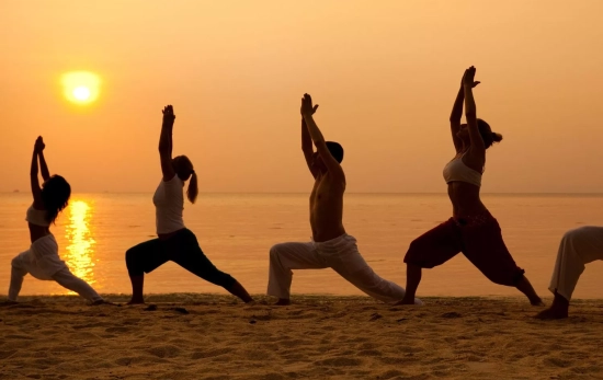 Varias personas practican stretching en la puesta de sol/ CANVA