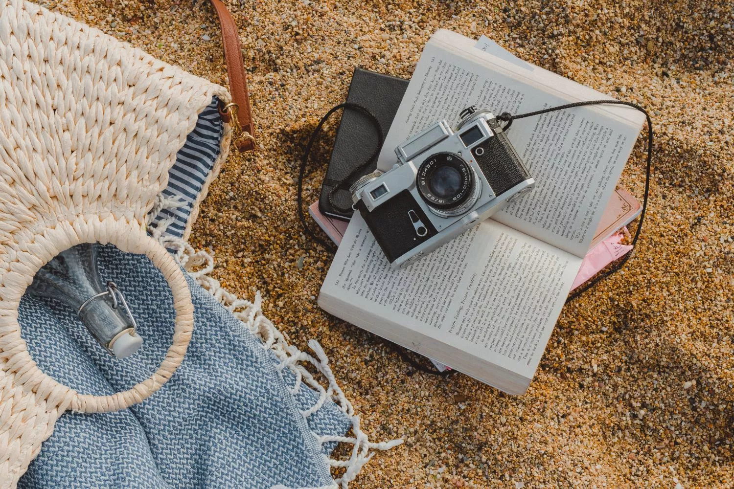 Una capazo, una toalla y objetos personales en la arena de la playa sin vigilancia/ CANVA