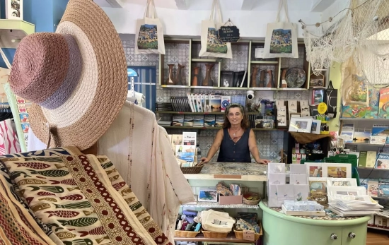 Un sombrero, prendas de moda y Neus tras el mostrador de Sa Botiga d'Alcaufar / TC Un sombrero, prendas de moda y Neus tras el mostrador de Sa Botiga d'Alcaufar / TC