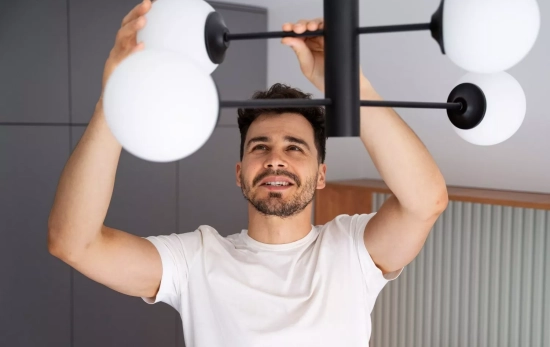 Una persona instala bombillas que emiten luz / FREEPIK