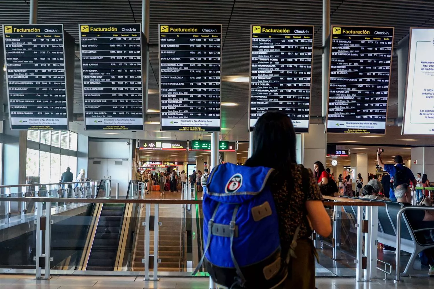 Una mujer con una mochila observa los paneles de facturación en un aeropuerto/  EUROPA PRESS - RICARDO RUBIO