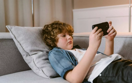 Un niño con un teléfono móvil haciendo scroll con reels/ PEXELS Un niño con un teléfono móvil haciendo scroll con reels/ PEXELS