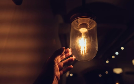 Una mano roza una bombilla que emite luz / FREEPIK - teksomolika Una mano roza una bombilla que emite luz / FREEPIK - teksomolika