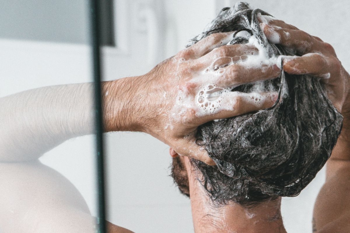 Un hombre se masajea el cabello con champú de yogur y probióticos / UNSPLASH
