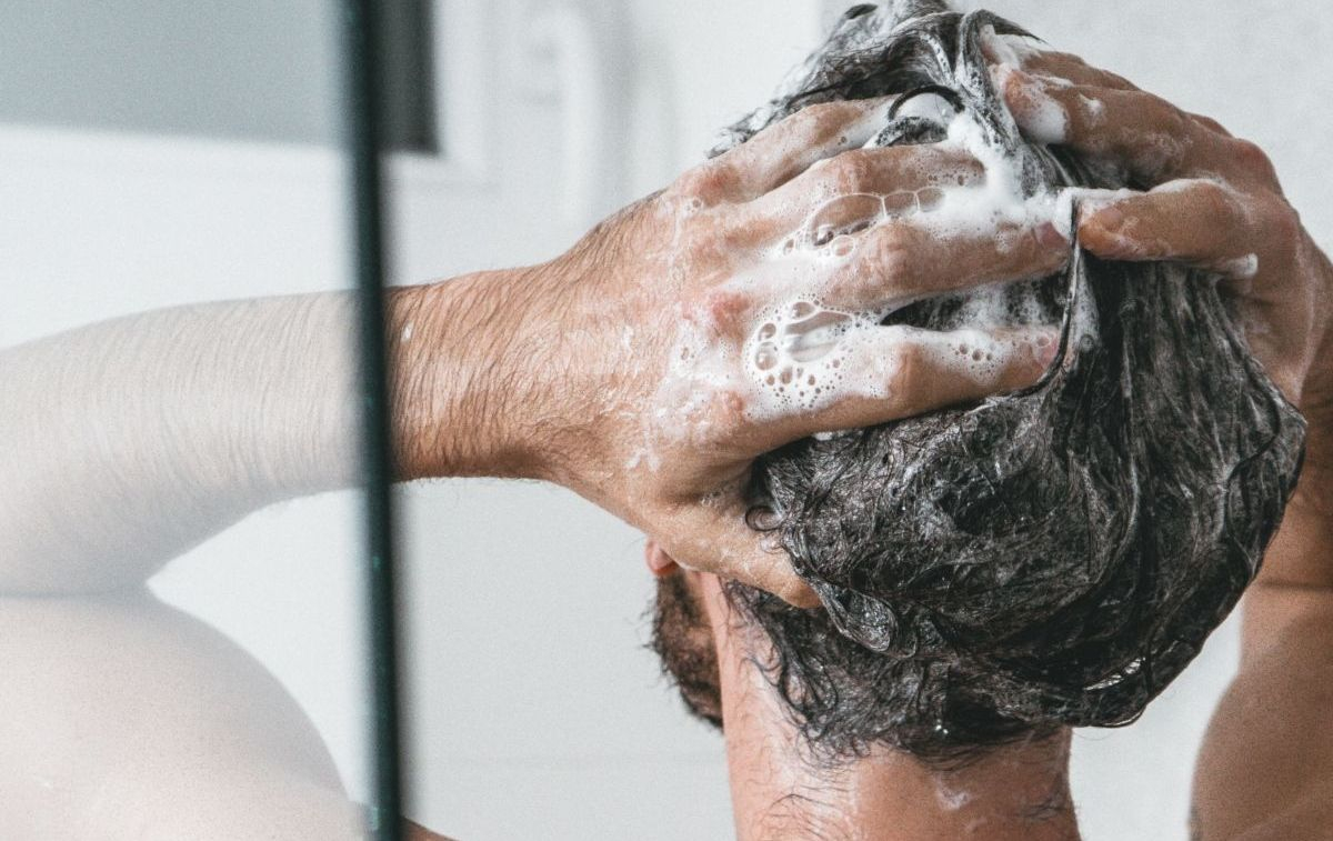 Un hombre se masajea el cabello con el champú / UNSPLASH