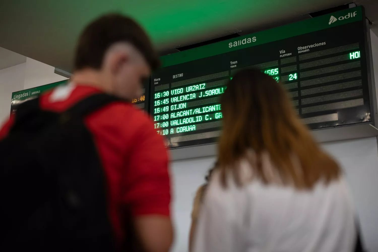 Varias personas consultan el panel de información de trenes en una estación / EP