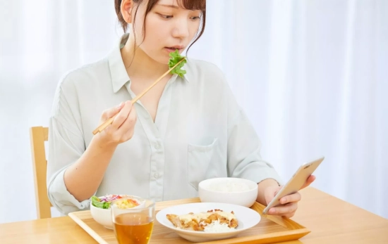 Una persona comiendo distraída con el móvil/ CANVA Una persona comiendo distraída con el móvil/ CANVA