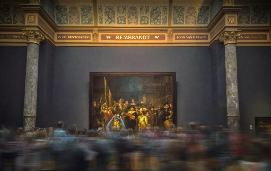Varios visitantes difuminados contemplan La ronda de noche, de Rembrandt Varios visitantes difuminados contemplan La ronda de noche, de Rembrandt