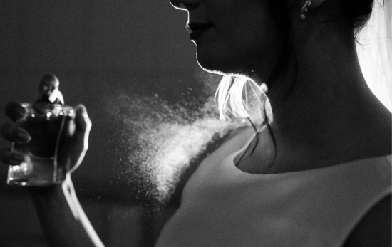 Una mujer perfumándose con un perfume árabe/ CANVA