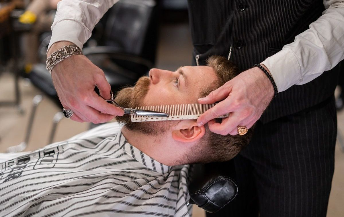 Un peluquero atiende a un cliente en una peluquería / PEXELS